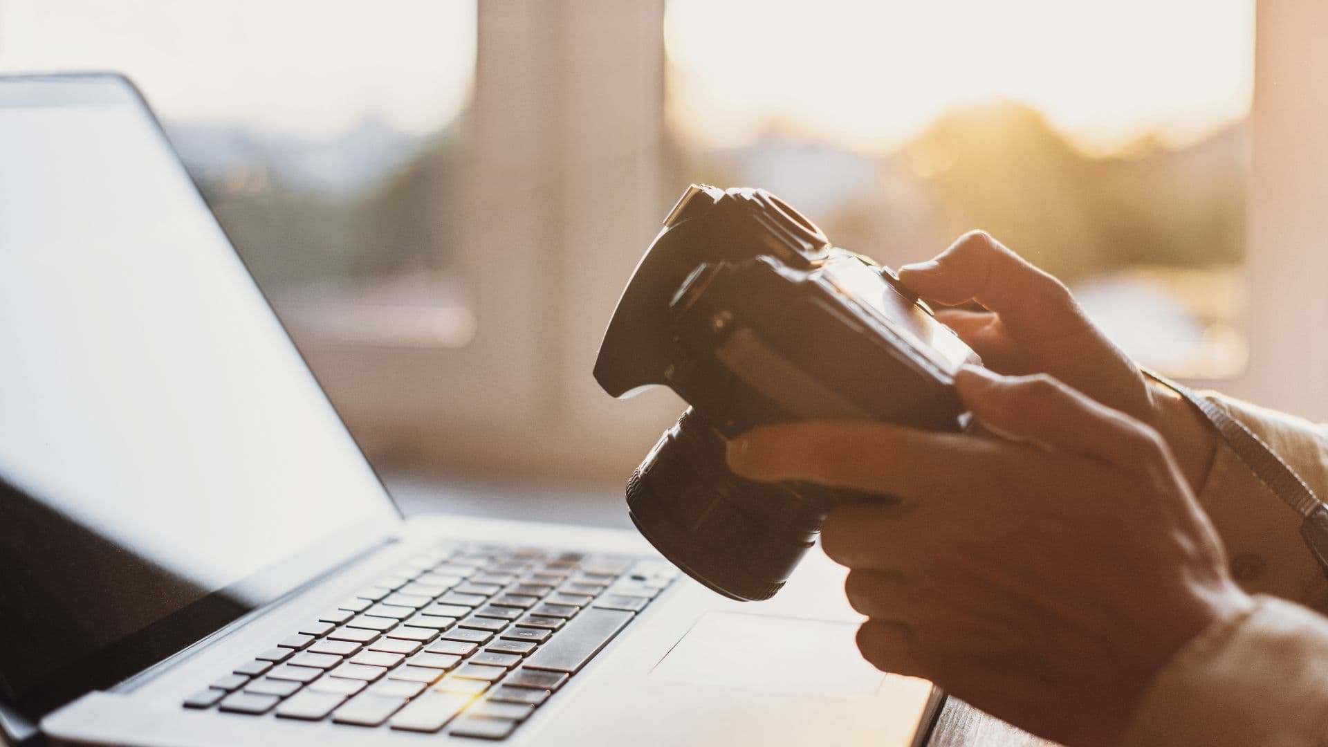 Someone holding a camera while sitting in front of a laptop