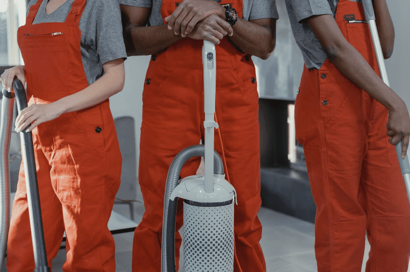 Cleaning crew standing side by side holding different cleaning equipment