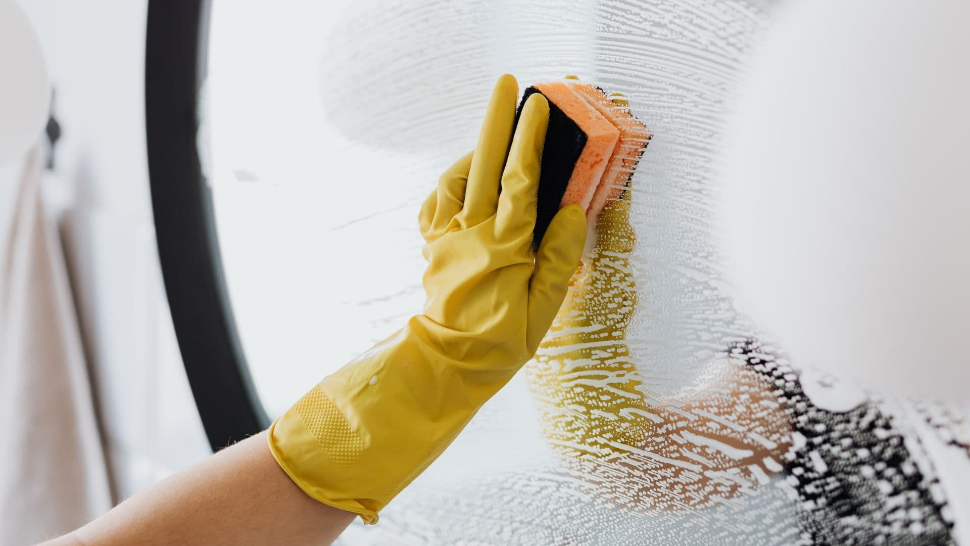 Airbnb cleaner holding a sponge to a soapy mirror