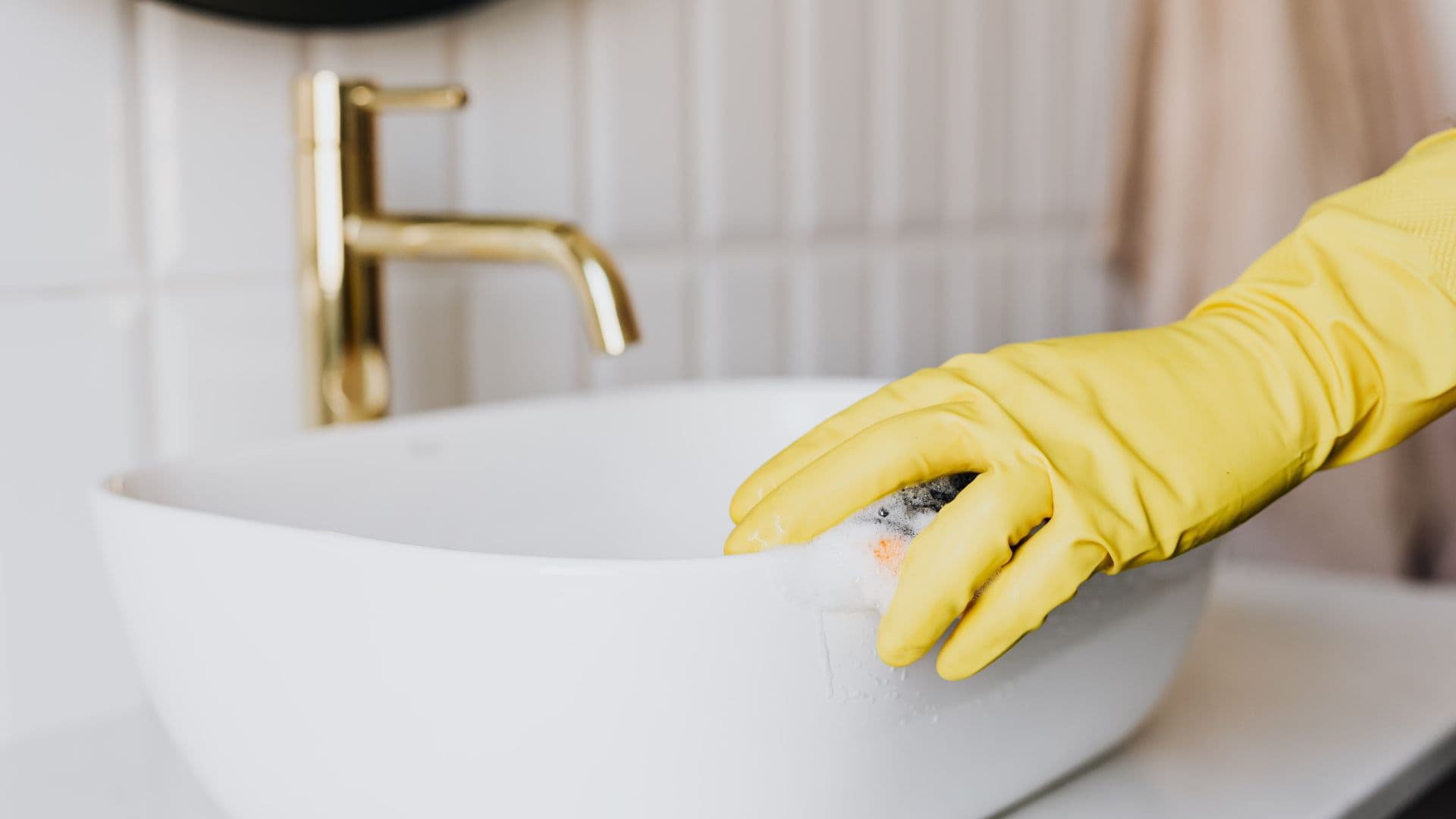 Airbnb cleaner cleaning bathroom sink with glove on