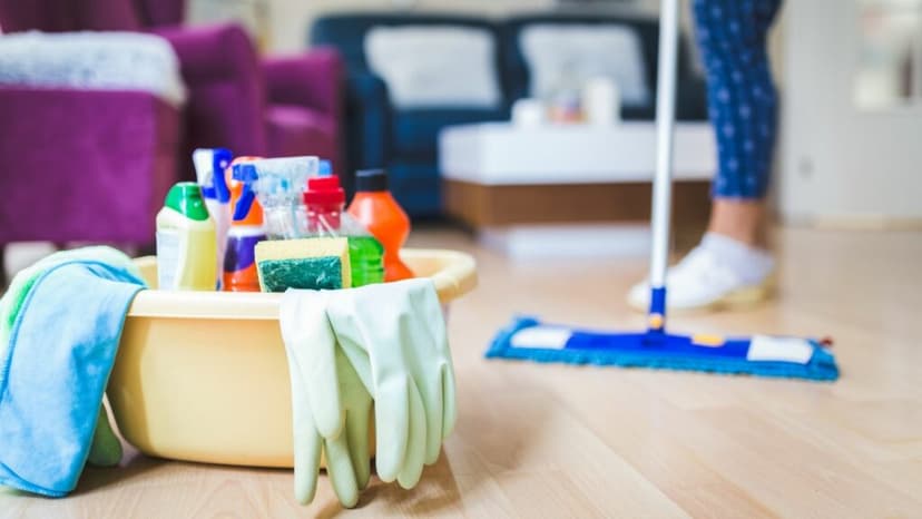 Lady mopping the floor with a filled cleaning caddy in the foreground