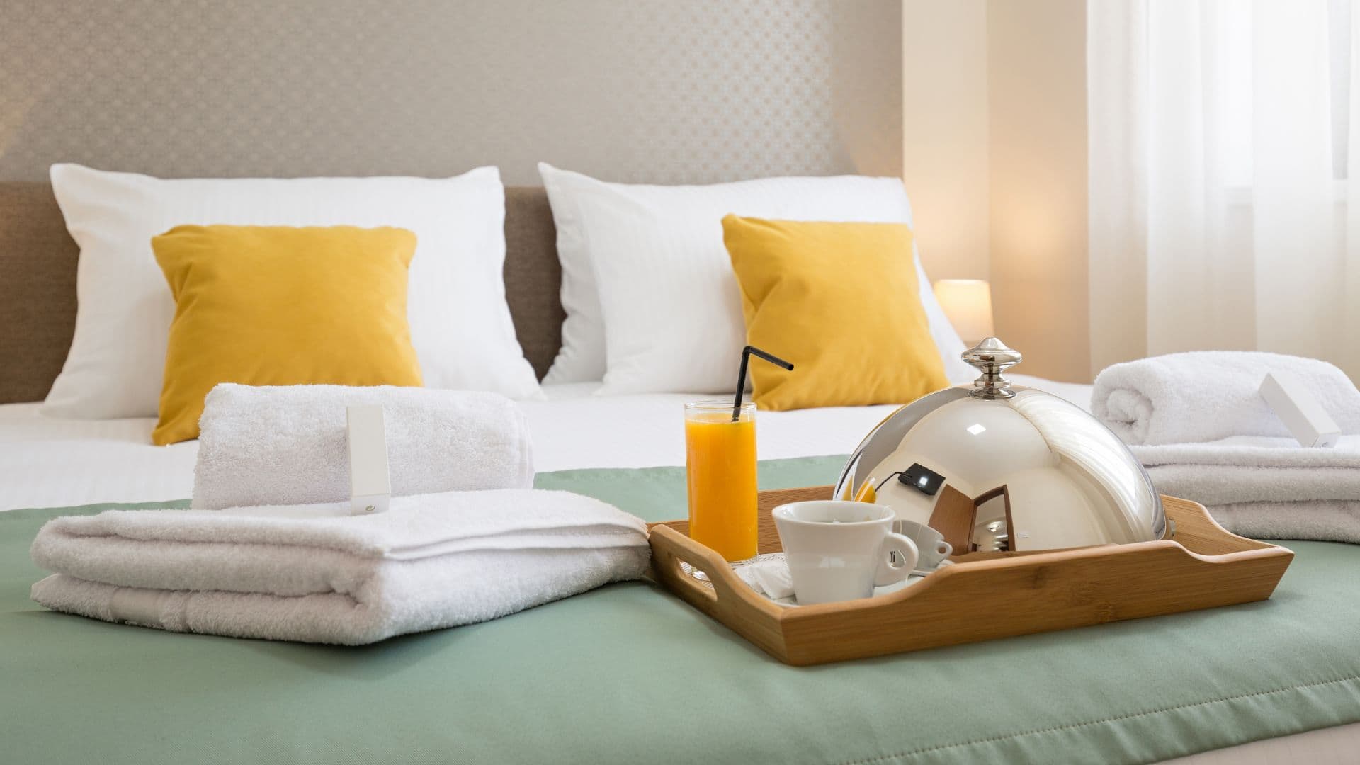 Bed with folded towels and a tray of covered food