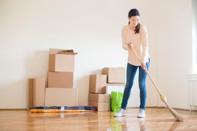 Woman sweeping floor with moving boxes in the background