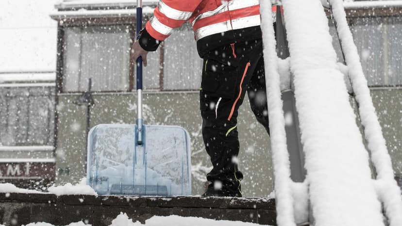 Male with a shovel removing snow from sidewalk